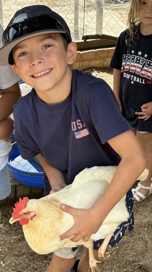 CJ smiling in the coop, holding Elsa the hen